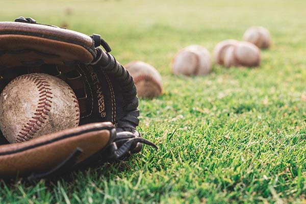 A baseball glove and baseballs shown on the field of a LEED certified MLB stadium implementing Marsden's innovative waste management and recycling plan