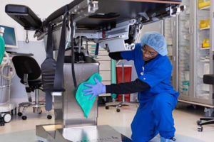 An environmental services associate cleans medical equipment as part of a comprehensive healthcare solution that meets the stringent healthcare operational requirements
