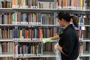 Janitorial associate cleaning university library book shelves as part of customized janitorial and specialty facility services that grow with the university