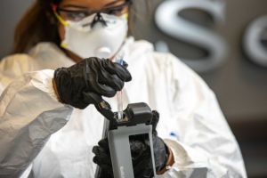 Technician wearing personal protective equipment performing analysis of swab testing to confirm that a commercial environment had been properly disinfected