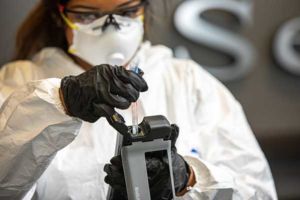 Technician wearing personal protective equipment performing analysis of swab testing to confirm that a commercial environment had been properly disinfected