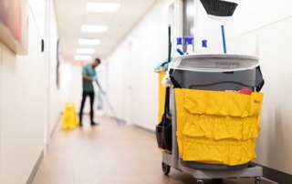 Commercial facility floor being professionally cleaned by a janitorial associate next to a caution wet floor sign