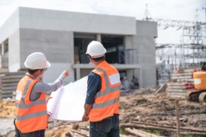 Two Emergency Response Services personnel stand in front of a commercial building construction site discussing action plans